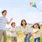 晴れた河川敷で凧あげを楽しむ家族